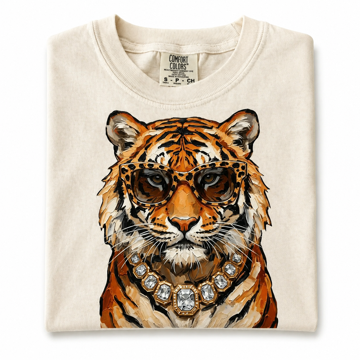 Folded cream Glam Tiger cropped T-shirt with tortoiseshell glasses and crystal necklace artwork.