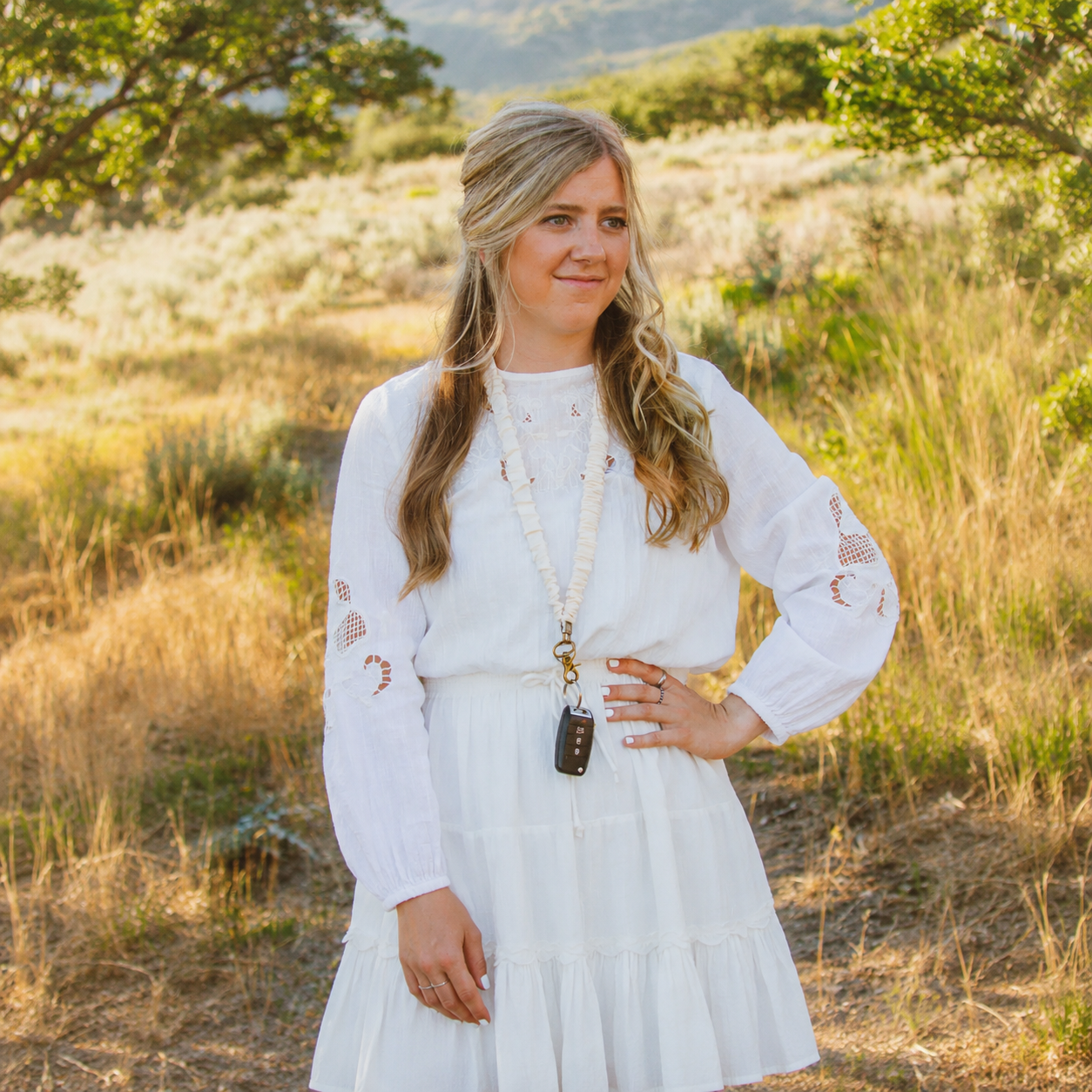 Model wearing a cream Oat Milk scrunchie lanyard with antique-brass-tone hardware.