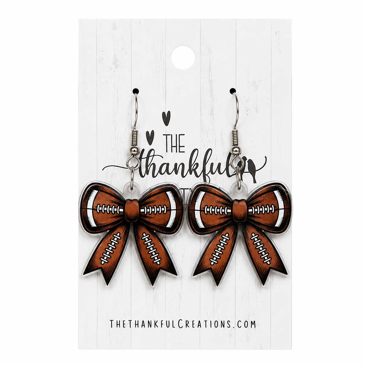 Football bow earrings in brown, black, and white on a white display card