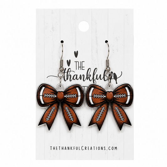 Football bow earrings in brown, black, and white on a white display card