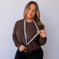 Model wearing a grey and white checkered scrunchie lanyard with antique-brass-tone hardware.