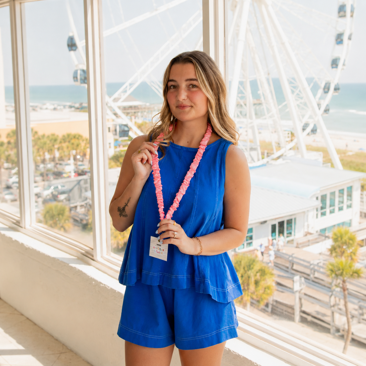 Model wearing a pink pencil-print scrunchie lanyard with an attached badge.