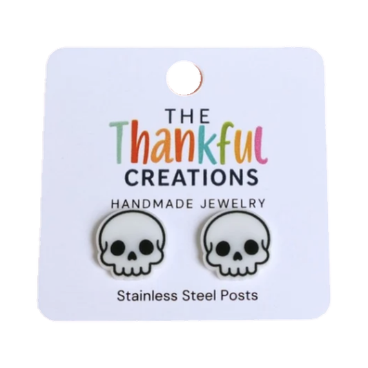 Black-and-white skull stud earrings displayed on a jewelry card.