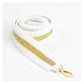 White and gold beaded purse strap coiled on a white background with gold-tone clasp